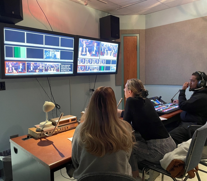 Three students in the control room viewing the show on overhead monitors