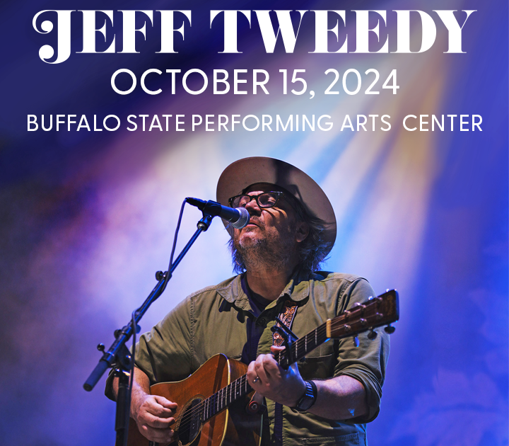 Jeff Tweedy playing a guitar and singing into a microphone