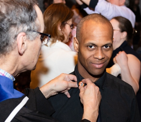 Faculty member pinning lapel pin on student recipient