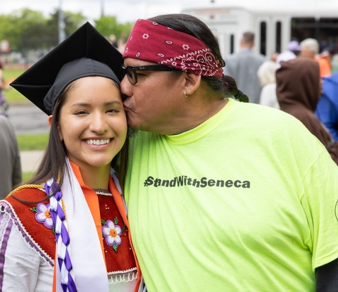 Proud relative kisses smiling graduate's cheek