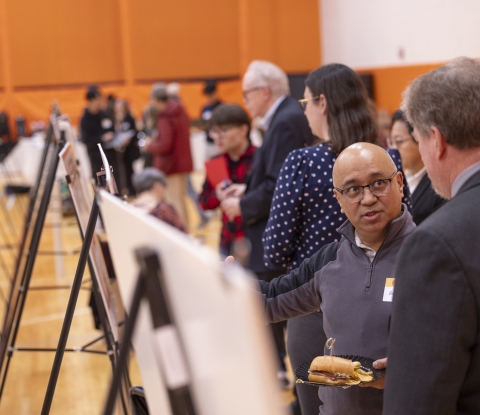 Wide view of the presenters and attendees showing many posters on display