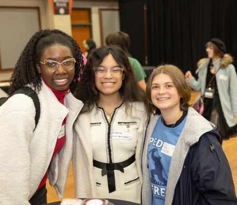 Three female students smile at the event