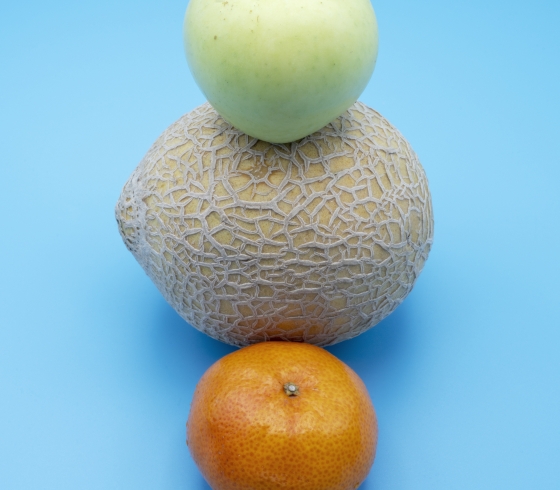 An apple, cantaloupe, and orange artfully stacked