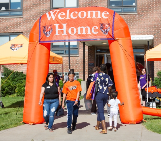 Students and families walking through a blow up sign that reads "Welcome Home"