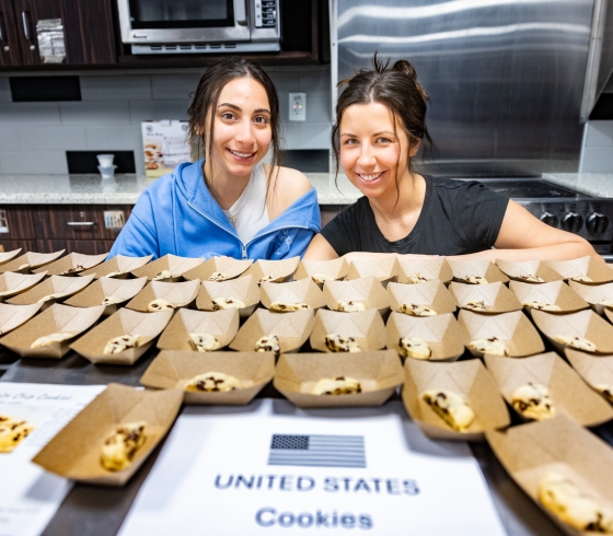 Students behind table of chocolate chip cookies