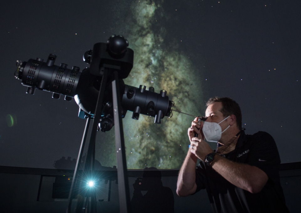 Howard George, Projection Systems Engineer with Seiler Planetarium Division, looking through projection telescope