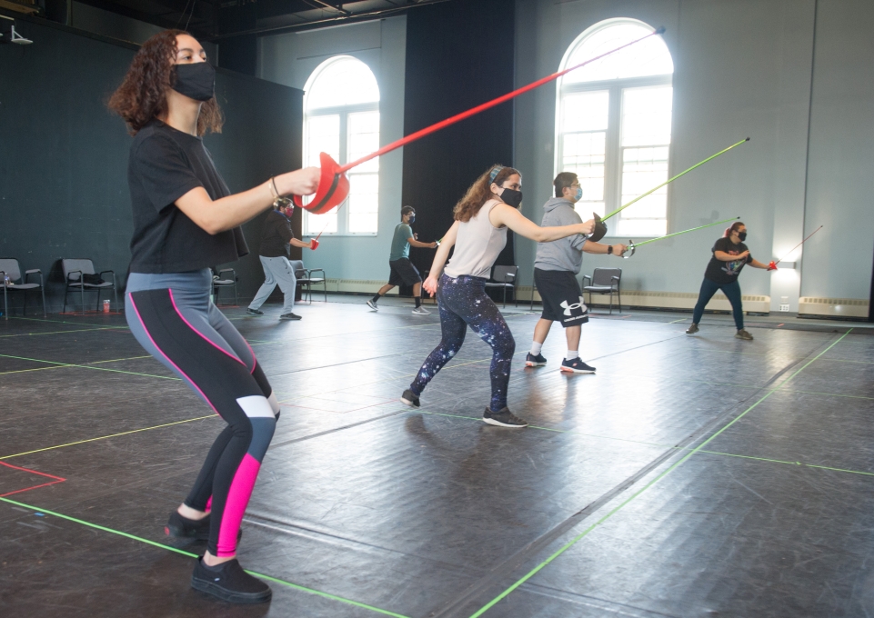 Students lined up with plastic swords raised