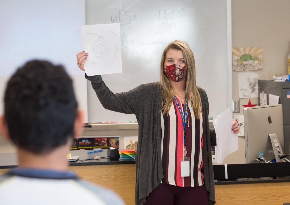 Student teacher Calista LeGault holds up a piece of paper in front of the class