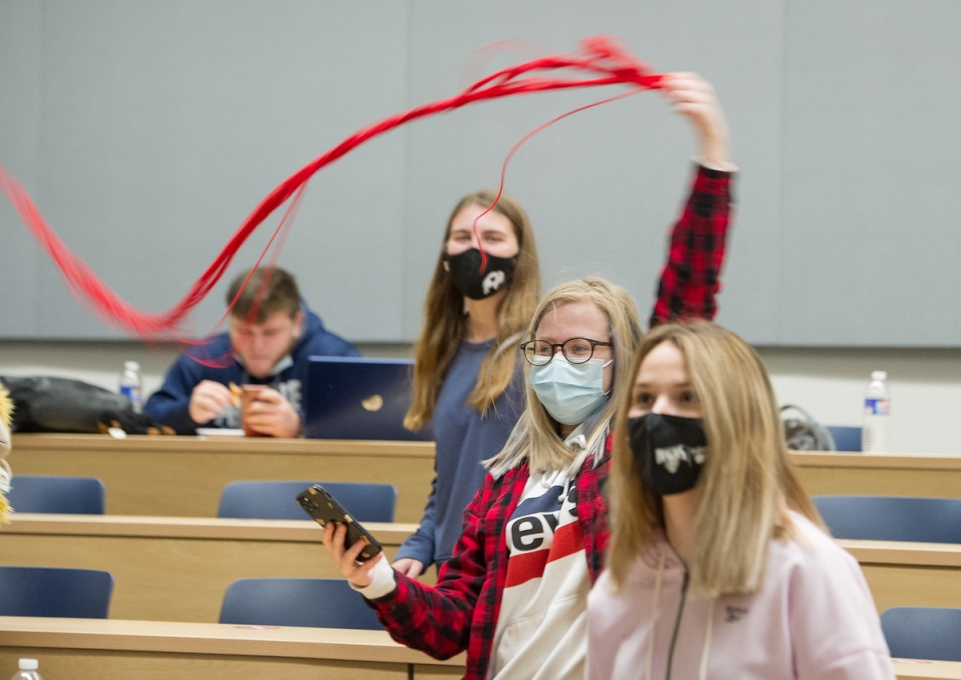 Student in the education learning community waving a red streamer