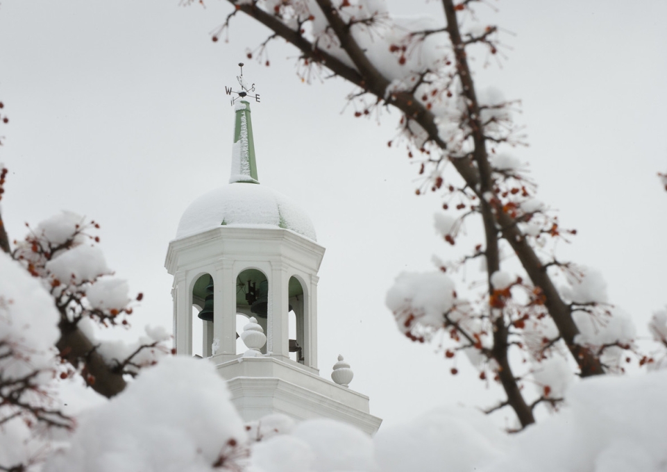 Snow covered Rockwell Hall bell tower surrounded by branches 