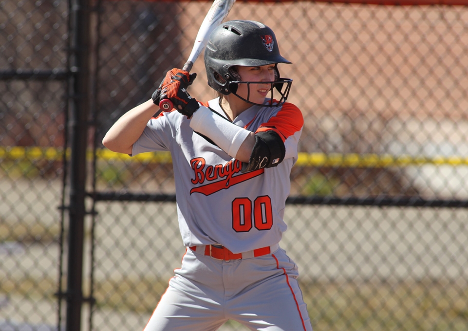 Oriana Castello in softball uniform, holding bat, in position ready to swing