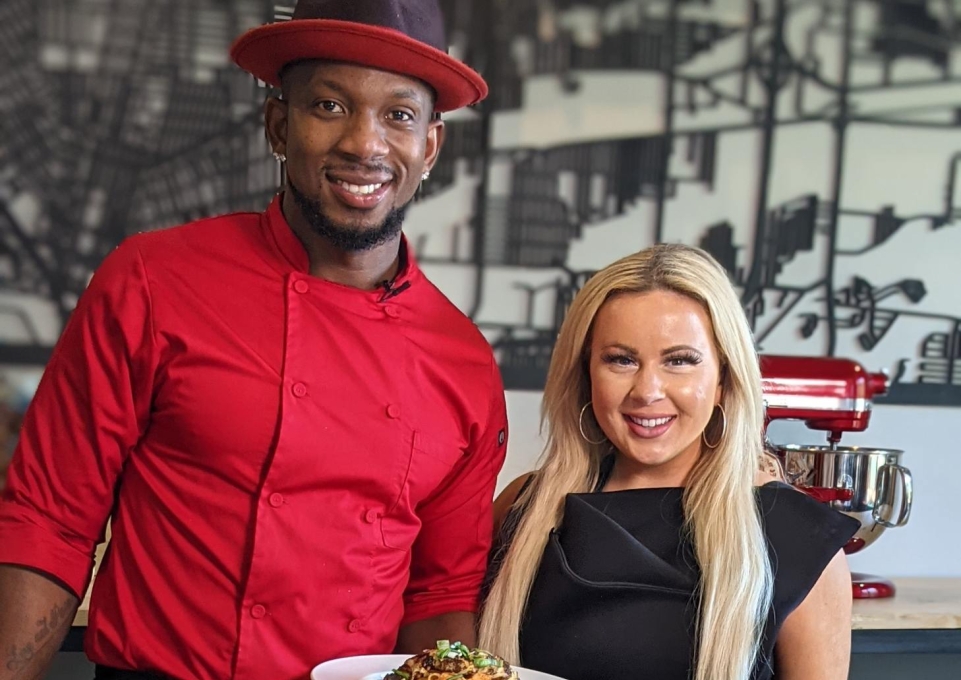 Bryan and Young pose with plate of food in the demo kitchen
