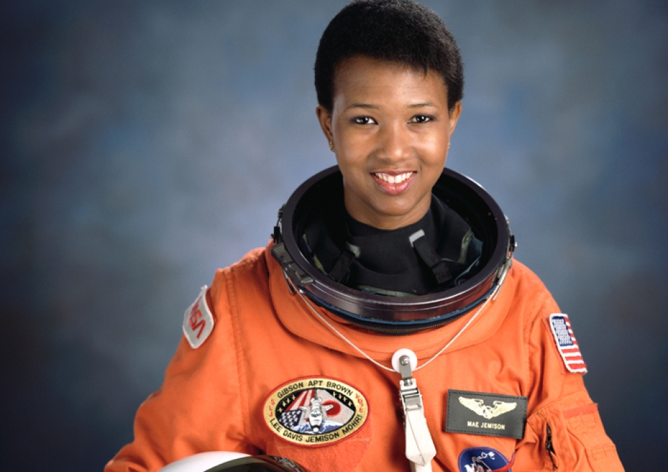 Mae Jemison in orange space suit holding helmet