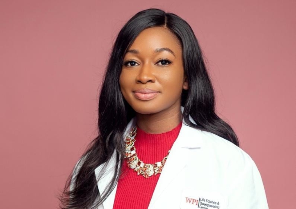 Sandra Jusu dressed in a white lab coat with WPI badge