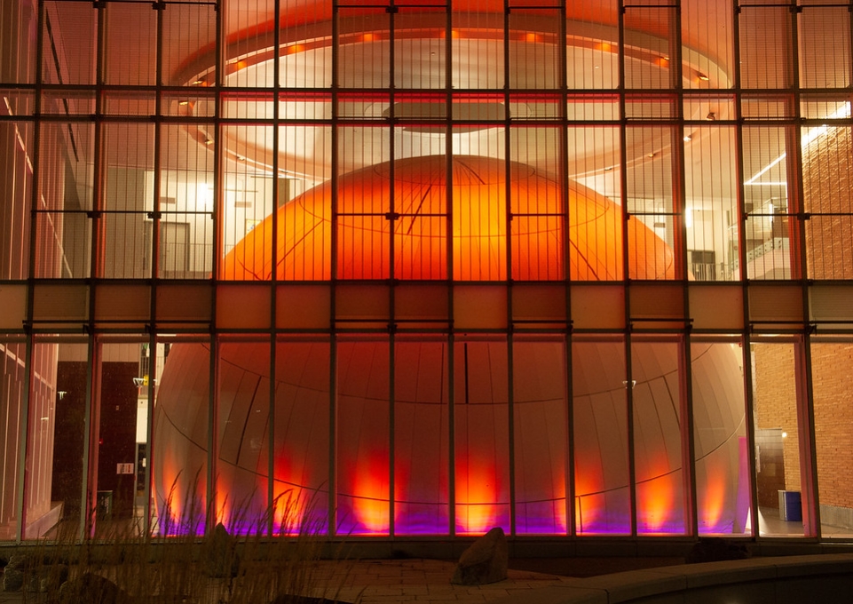 View of the planetarium lighted orange as seen from outside the Science and Math Complex