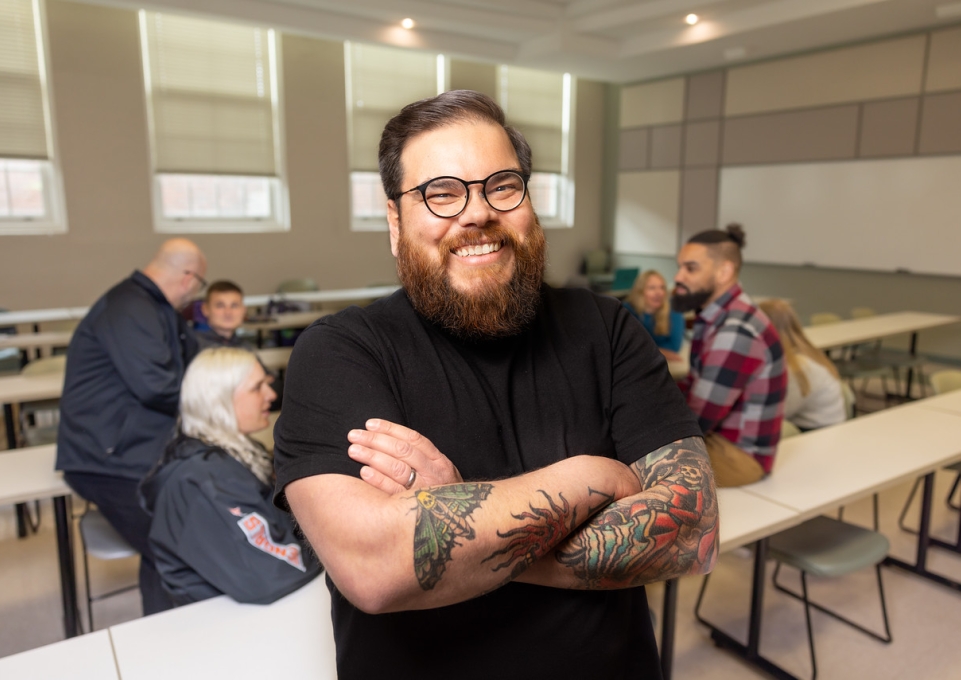 Hermen Diaz standing in a classroom, smiling with arms crossed