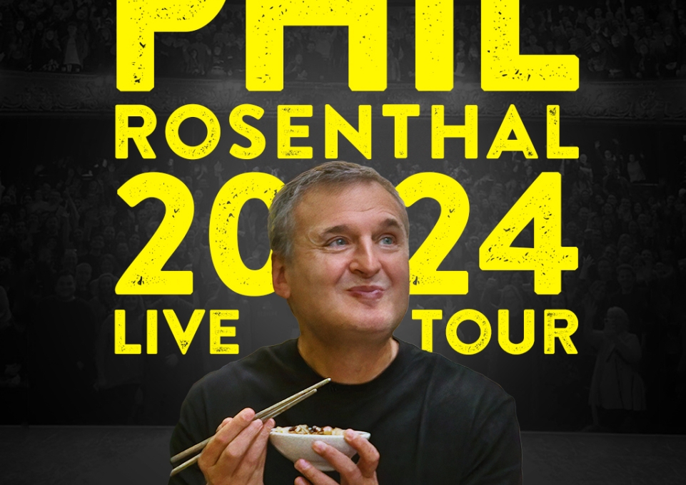 Phil Rosenthal smiling and eating with chopsticks