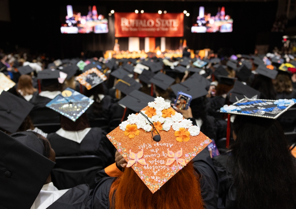 A group of students with graduation caps facing the stage