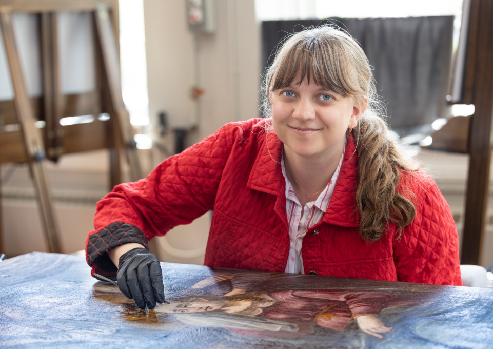 A female student working on conserving a painting